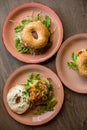 Vertical various delicious sesame donuts burgers with cheese, meat filling, greenery filling, sauce served up on plates