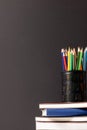 Vertical video of composition of crayons in container on stack of books on grey background