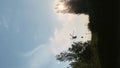Vertical video silhouette of fire helicopter flying up from water reservoir in sunshine of sunset in Spain. Rescue