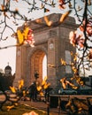 Vertical view of the arch of triumph through the tree branches under the blue sky in Bucharest