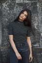 Vertical view. Beauty frontal portrait of a cheerful girl with straight hair, with makeup, supported by a black wall.