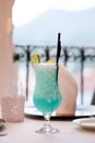 Vertical view of a blue cocktail with slices of tangerine served on a table