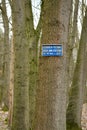 A vertical view of a tree with the sign Prohibited to pass for unauthorized persons in Dutch