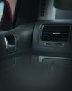 Vertical view of a car dashboard air vent black materials red mirror chrome accents