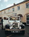 Vertical view of a classic Rolls-Royce wedding car parked before a building