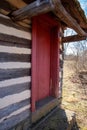 vertical view of colonial log cabin red door