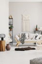 Vertical view of cozy living room with stylish couch with pillows, furry carpet and white macrame on the wall Royalty Free Stock Photo