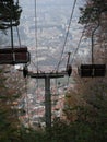 Vertical view of the empty cabins and wires of telecabin before the cityscape Royalty Free Stock Photo