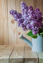 Vertical view flowers of lilac in white watering can on wood