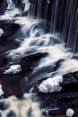 Vertical view of the foamy waves of a river flowing down the rocks in daylight in a forest Royalty Free Stock Photo