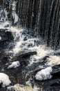 Vertical view of the foamy waves of a river flowing down the rocks in daylight in a forest Royalty Free Stock Photo