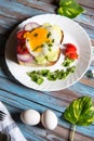 Vertical view of fried eggs with bacon and vegetables on bun bread Royalty Free Stock Photo
