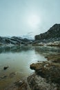 Vertical view of a frozen lake in front of a massive mountain with snow and copy space