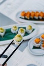 Vertical view of the hands holding wasabi sushi and rolls with wooden chopsticks