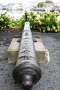 Old cannon mounted in park with soft focus boats and water in background Royalty Free Stock Photo