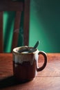 A vertical view of hot brown cup of ginger tea with steam, tea bag and spoon on rustic wooden table Royalty Free Stock Photo