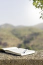 Vertical view of isolated open notebook with a pen on it and natural background behind Royalty Free Stock Photo