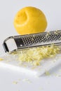 Vertical view of lemon zest on a marble slab with a microplane and lemon in behind. Royalty Free Stock Photo