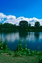 A vertical view of a long exposure of an island in a river with a smooth waterfront with a background of blue sky with clouds in a Royalty Free Stock Photo