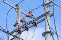 Vertical view looking up at electrical poles and wiring against a blue sky with white clouds Royalty Free Stock Photo