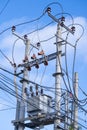 Vertical view looking up at electrical poles and wiring against a blue sky with white clouds Royalty Free Stock Photo