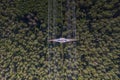 Vertical view on a metal power pole with high voltage wires over forest trees