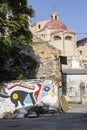 Vertical view of a painted wall on a street in Palermo, Sicily, with the dome of a church at the bottom