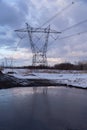 Vertical view of power towers and electric lines reflected in a large puddle