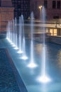 Vertical view on row of white water fountains at dusk