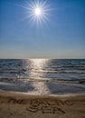 Vertical view of a sandy beach and gentle ocean under a blue sky with a sun star and text The Baltic Sea written in the sand Royalty Free Stock Photo