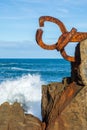 Vertical view of a sculpture of the Peine del Viento, with waves and rocks, a sunny winter day