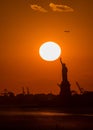 Vertical view of silhouettes of the Statue of Liberty and buildings at an orange scenic sunset Royalty Free Stock Photo