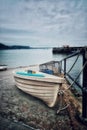 Vertical view of a small white wooden row boat tied to the bars with a rope at a dock Royalty Free Stock Photo