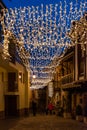 Vertical view of a street illuminated at Christmas with a star and lights, background with people walking between the stone houses Royalty Free Stock Photo