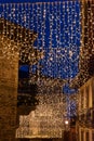 Vertical view of a street illuminated at Christmas with a star and lights, background with people walking between the stone houses Royalty Free Stock Photo