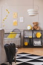 Vertical view of stylish grey and yellow baby bedroom