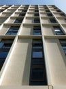 Vertical view of a tall concrete angular modern high building with geometric white details against a blue sky Royalty Free Stock Photo