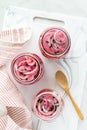 Vertical view of three jars of pickled red onions on a white cutting board.