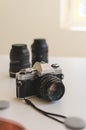 Vintage 35mm analogue camera surrounded with lenses and film on a table