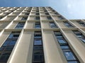 Vertical view of a white high white concrete building development with sunlight and blue sunny sky reflected in the windows Royalty Free Stock Photo