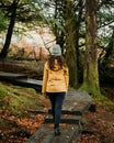 Vertical view of a woman from behind, walking on the pathway of a park in Autumn