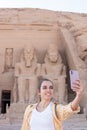 Vertical view of young smiling tourist woman taking a selfie in the facade entrance of the Abu simbel temple in Egypt Royalty Free Stock Photo