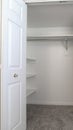 Vertical Walk in closet with double hinged doors plain white wall and gray floor carpet