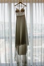 Vertical of a wedding dress on a hanger against a window Royalty Free Stock Photo