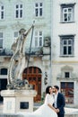 Vertical wedding portrait of the handsome groom softly kissing the gorgeous bride in the cheek while sitting on the old Royalty Free Stock Photo