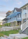 Vertical Whispy white clouds Three large houses with white picket fence and verandas at the entrance in Daybreak, Utah