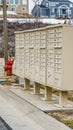 Vertical White metal cluster mailboxes and red fire hydrant along a concrete road