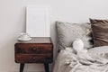 Vertical white picture frame mockup. Retro wooden bedside table. Modern white ceramic vase with dry Lagurus ovatus grass