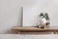 Vertical white picture frame mockup. Vintage wooden bench, table. Modern vase with pine tree branches. Paper baubles on