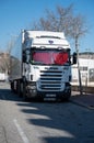 Vertical of white Scania R440 truck with red curtains parked on the street.